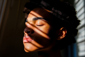 Close-up of a young African American man with eyes closed basking in the sunlight, evoking a sense of peace and tranquility.
