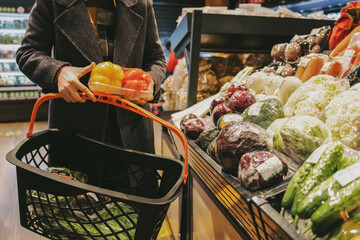 Consumer Selecting Fresh Produce in Supermarket Aisle