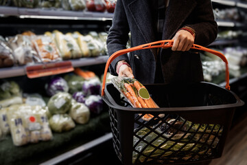 Consumer Holding Basket with Fresh Vegetables in Supermarket
