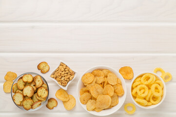 Various unhealthy snacks on wooden background, top view