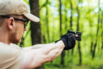 instructor with gun in forest leads aiming and posing on camera