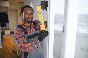 a african repairman repairs, adjusts or installs metal-plastic windows in the apartment
