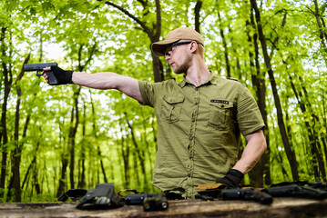 guy in the woods tests his weapons for shooting sports