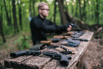 guy in the woods tests his weapons for shooting sports