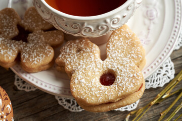 Homemade Linzer cookie in the shape of chicken near a cup of tea, with Easter egg in the foreground