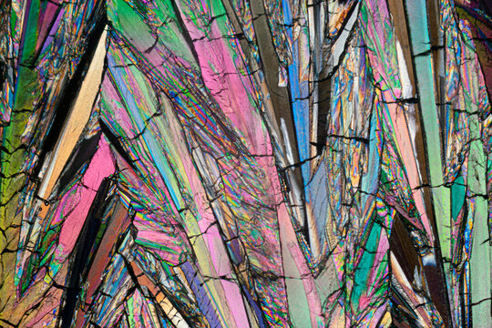 Close-up microscope image showcasing the intricate, colorful patterns of erythritol sugar crystals with varied hues and textures