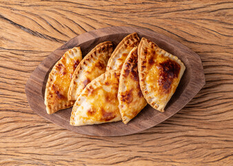 Typical brazilian snack baked pastel on a plate over wooden table