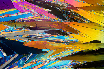 Microscopic image of erythritol sugar crystals forming a sharp-edged, colorful mosaic with a sense of movement