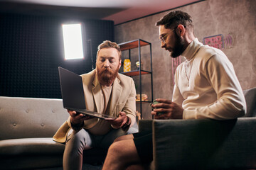 good looking stylish men in elegant attires with coffee and laptop discussing interview questions