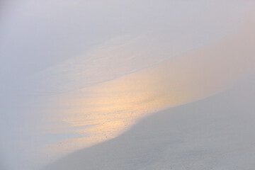 Minimalist image of a subtle sand gradient with the gentle gleam of a sunset reflected on the shore