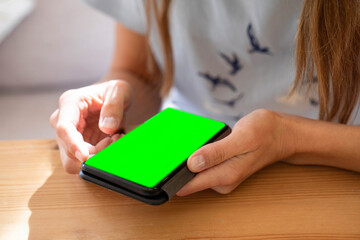 Young woman using smartphone with green screen for scrolling news, photos, online working, shopping