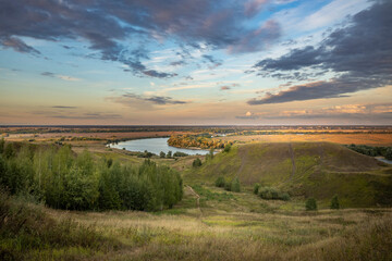 Beautiful stage lighting of an epic landscape with river and water meadows, dramatic sky above the horizon