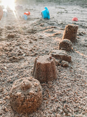 Children playing on the beach with figures and sand castles, homes in a summer evening