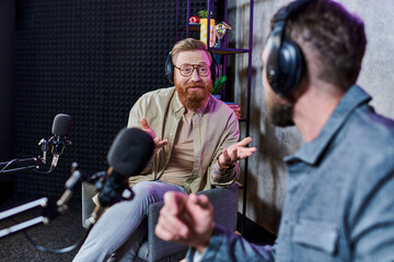 bearded handsome interviewer and his guest with headphones in studio discussing questions, podcast