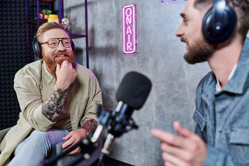 bearded handsome interviewer and his guest with headphones in studio discussing questions, podcast