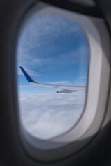 飛行機の内窓から見える翼と青空