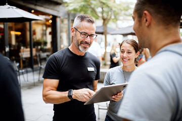 Man Standing Next to Woman Holding a Tablet in Business Setting