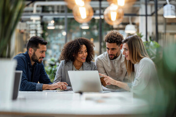 Group of People Sitting at a Table, Looking at a Laptop in a Business Meeting