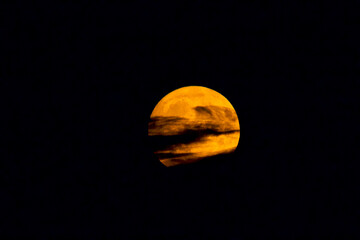 Red supermoon embraced by clouds in the sky