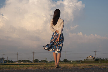 夏の夕方の雲を見つめる女性の後ろ姿