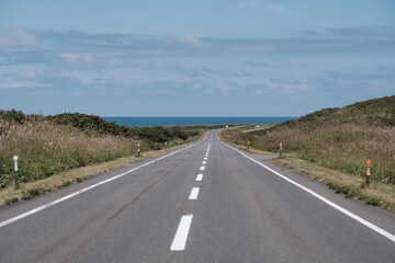 秋の北海道の海が見える下り坂の道路
