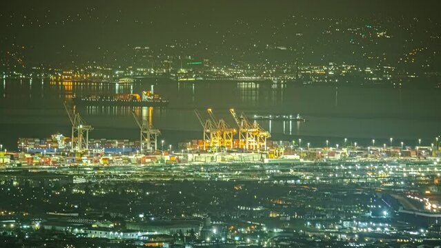 High angle night timelapse over illuminated Oakland Port with traffic flow