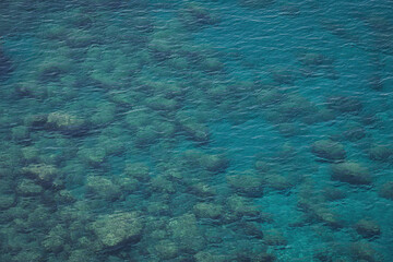 Aerial view of calm turquoise sea water and rocks from molten lava from drone. Pattern of sea surface and rocky shore. Liguria, Italy. turquoise water of Ligurian sea.
