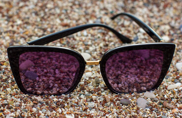 Sunglasses lying on a pebble beach close-up
