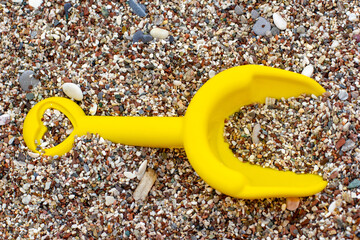 A child's yellow plastic shovel for playing in the sandbox lies on the sea shore on a pebble beach...