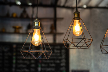 Classic style lightbulb ceiling lamp with iron cage glowing in orange light shade. Interior...
