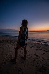 Silhouette of a beautiful woman from behind admiring the sunset and coastal tranquility on...