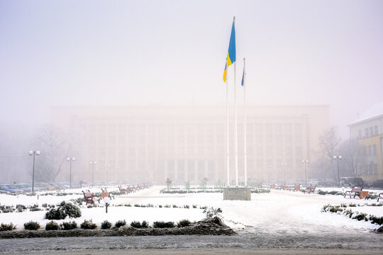uzhhorod, ukraine - 26 JAN 2017: ukrainian and european union flags on the narodna square. cityscape on a misty morning in winter. frosty and uncertain weather