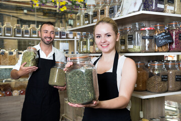 Sellers posing with banks of dried herbs in store