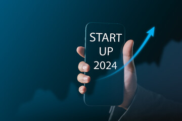 2024 Startup Boom Businessman's Hand Holds Smartphone, Unveiling Profitable Trends, Government Support, and Growing Competition