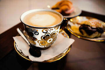 cup of coffee with milk served on the breakfast table, decorated in antique style