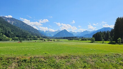 A picturesque scene of a grassy field with majestic mountains towering in the background, creating a serene landscape.