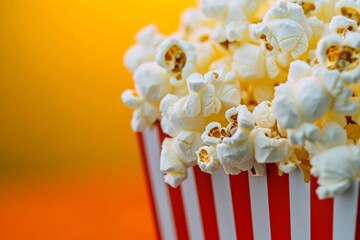 Bright yellow background enhances popcorn in a red striped box, movie delight