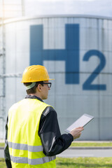 Engineer with tablet computer on a background of Hydrogen factory.
