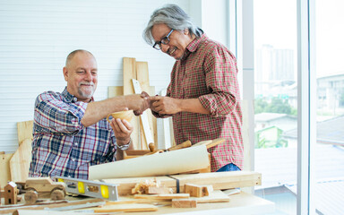 Two senior mixed race diverse happy retired old male woodworkers or carpenters wearing check...