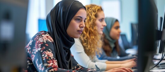 Colleagues from different backgrounds work together, with an experienced person guiding and teaching a female trainee on computer skills.