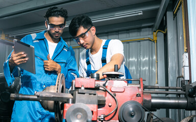 Two adult handsome male mechanics wearing uniform, using machine for fix, repair car or automobile components, teamwork helping, working in car maintenance service center or shop. Industry Concept.
