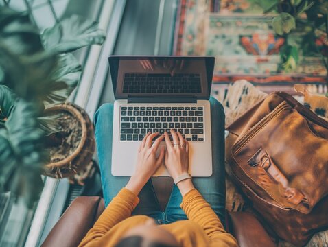 Top view of a person's hands typing on a laptop in an airport lounge