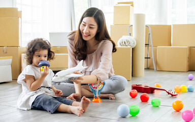 Beautiful adult Asian woman or mother and little cute daughter moving new house, home or apartment,...