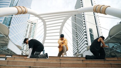 Group of happy break dancer walk down stair while dancing together at city. Professional hipster perform energetic footstep while looking at camera. Low angle camera. Outdoor sport 2024. Sprightly.
