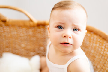 little baby girl close-up or portrait of a baby with blue eyes in a wicker cradle at home in the...