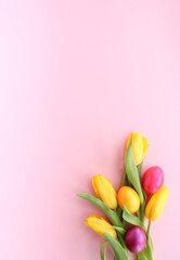 A Vibrant Easter Bouquet: Yellow Tulips and Colorful Eggs on a Soft Pink Background