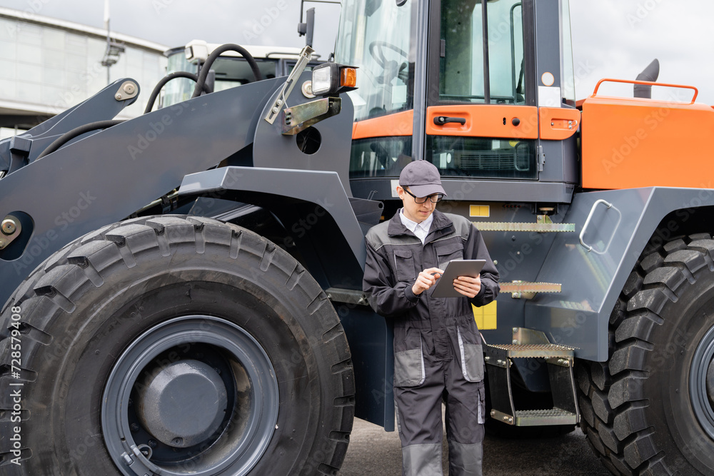 Poster Serviceman with digital tablet on a background of the tractor.
