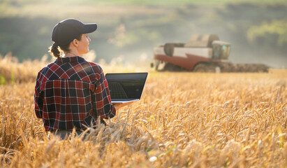 Woman farmer with digital tablet on a background of harvester. Smart farming concept
