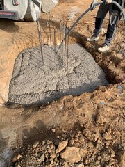 Pouring concrete into footings in a construction site. Worker using a concrete vibrator to expand the concrete into foundations. 