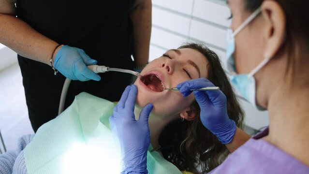 Close-up of the hands of a dentist doing oral examination with mirror